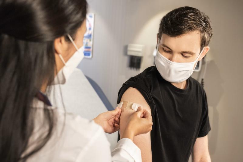 Doctor putting a band aid on young mans arm